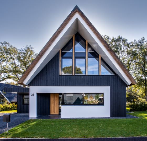 Vrijstaand nieuwbouw huis met rieten dak en mooi gazon, voorbeeld van een droomhuis.